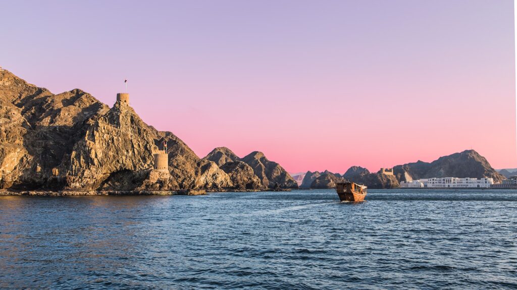 white and brown lighthouse on brown rock formation beside body of water during daytime